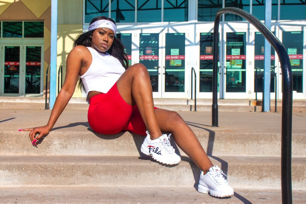 woman in red tank top and white nike sneakers sitting on concrete bench during daytime